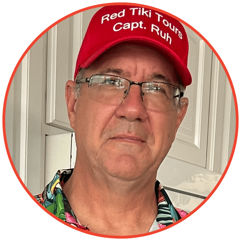 Man in red cap and colorful shirt standing indoors.